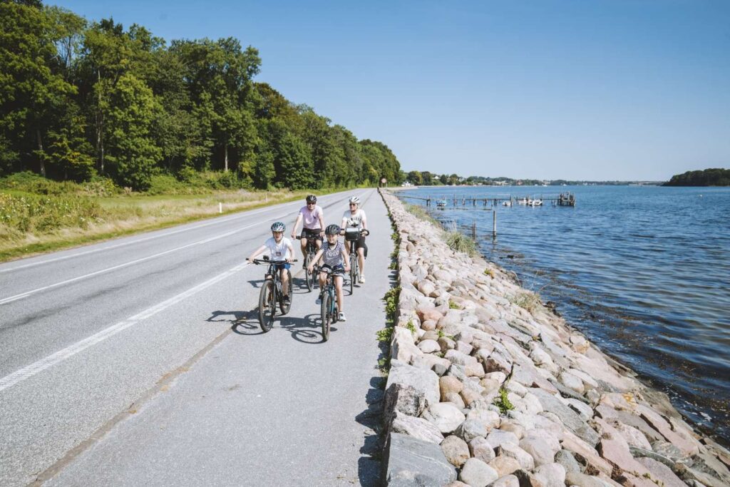 Familie på cykeltur langs vandet ved Sønderballe Strand Camping