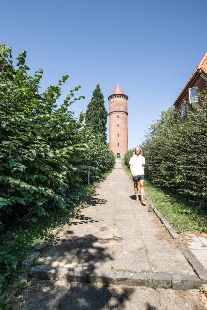 Mand der går foran et rødt vandtårn i Haderslev