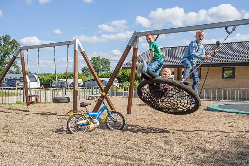 Børn der gynger på legepladsen