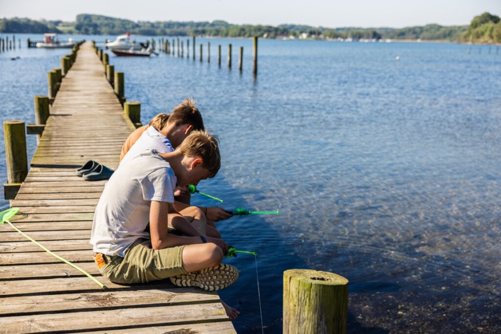 Børn fisker efter krapper på badebro ved Sønderballe Strand Camping