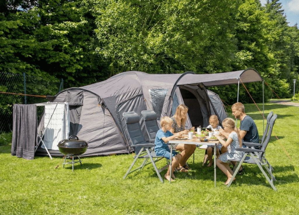 Familie spiser aftensmad foran telt på campingplads